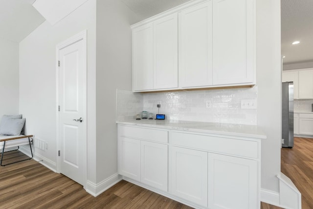 kitchen with freestanding refrigerator, tasteful backsplash, white cabinetry, wood finished floors, and light countertops