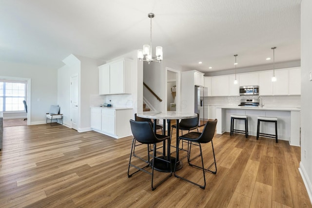 dining space featuring baseboards, a chandelier, recessed lighting, stairway, and wood finished floors