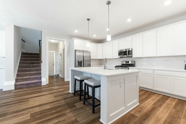 kitchen with dark wood-style floors, backsplash, white cabinets, stainless steel appliances, and a sink