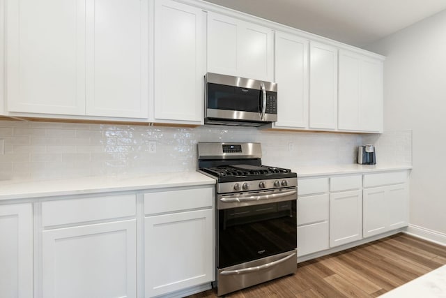 kitchen featuring light wood-style floors, white cabinets, appliances with stainless steel finishes, light countertops, and decorative backsplash
