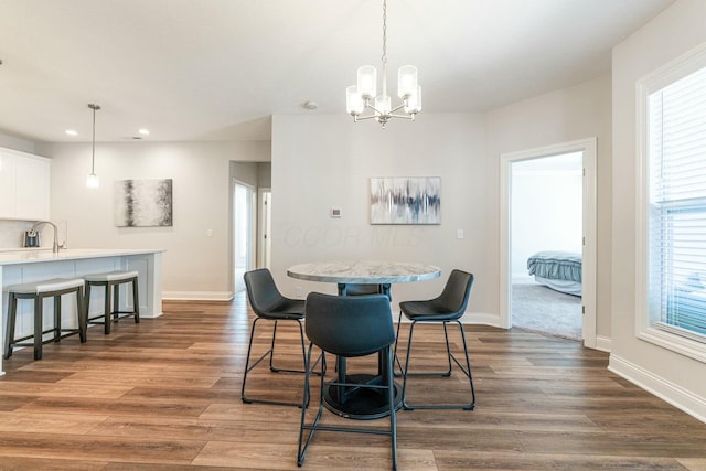 dining area with dark wood-type flooring, an inviting chandelier, and a wealth of natural light