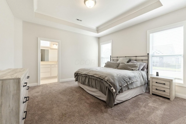 bedroom with a tray ceiling, light colored carpet, baseboards, and visible vents