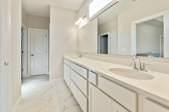 bathroom featuring baseboards, double vanity, marble finish floor, and a sink