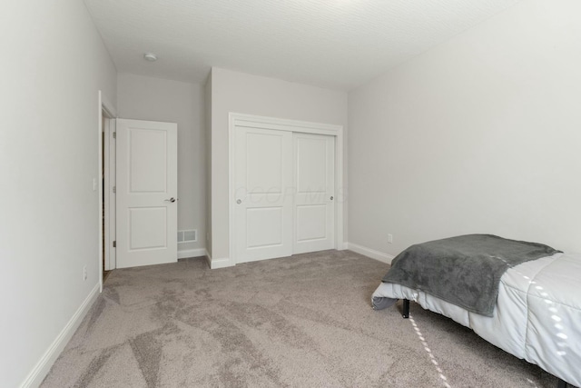 bedroom featuring a closet, baseboards, visible vents, carpet, and a textured ceiling