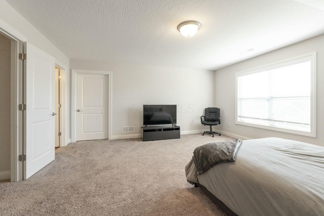 bedroom with a textured ceiling, visible vents, baseboards, and carpet