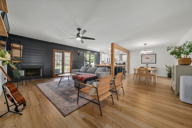 living area with ceiling fan, light wood finished floors, baseboards, and a fireplace