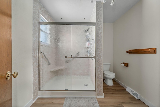 bathroom with toilet, a stall shower, wood finished floors, and visible vents