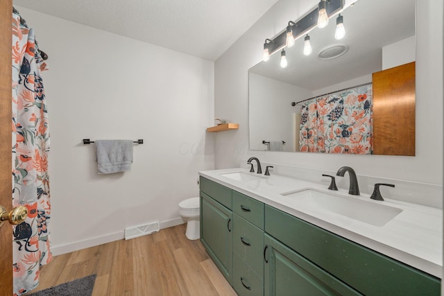 bathroom featuring a sink, visible vents, toilet, and wood finished floors