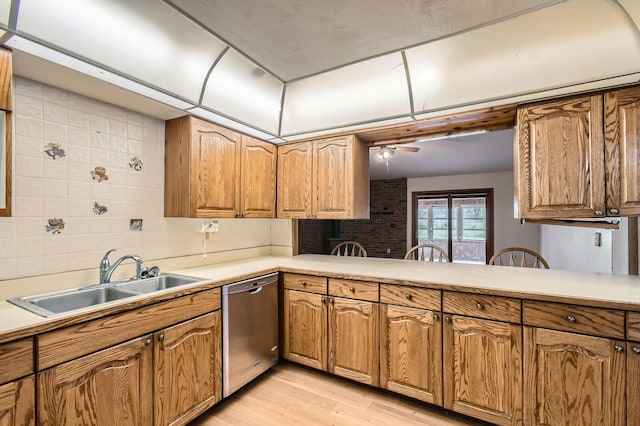 kitchen featuring a sink, light countertops, stainless steel dishwasher, and light wood finished floors
