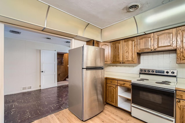 kitchen with light wood-type flooring, electric range, visible vents, and freestanding refrigerator