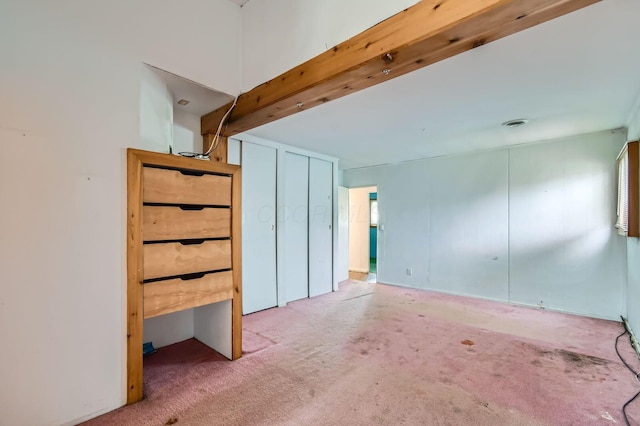unfurnished bedroom featuring beamed ceiling and carpet floors