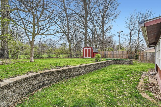view of yard with a fenced backyard, an outdoor structure, and a storage unit