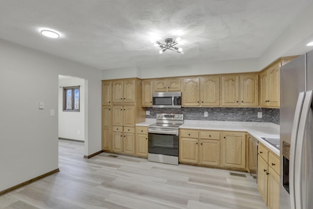 8015 Alspach Rd NW, Lancaster, OH 43130 - kitchen with light brown cabinets, light countertops, light wood-type flooring, appliances with stainless steel finishes, and backsplash