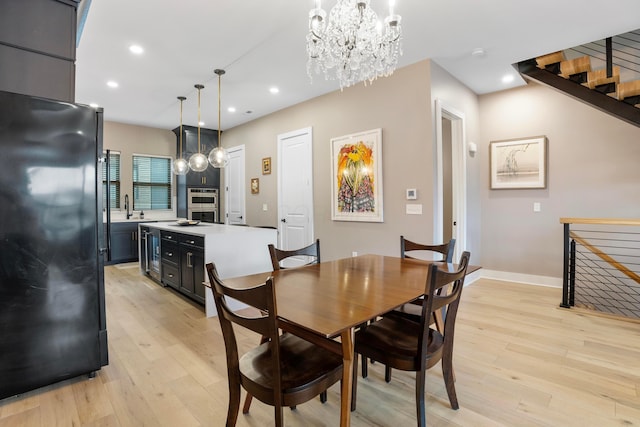 dining area featuring light wood finished floors, baseboards, recessed lighting, a chandelier, and beverage cooler