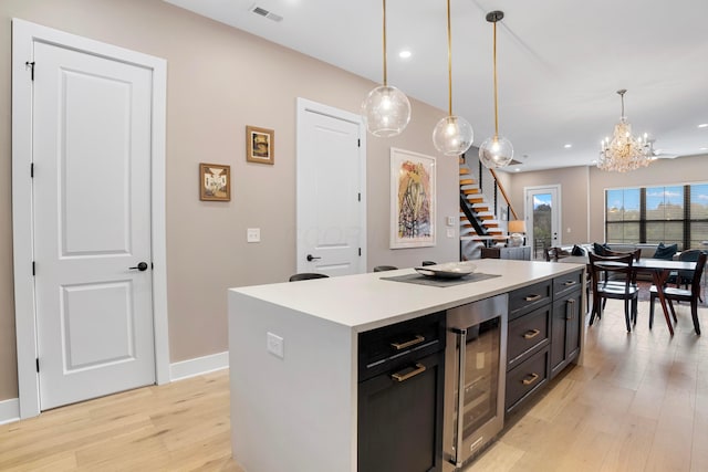 kitchen with a chandelier, pendant lighting, light wood-style flooring, wine cooler, and visible vents