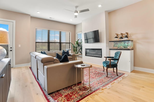 living room featuring light wood finished floors, baseboards, recessed lighting, ceiling fan, and a fireplace