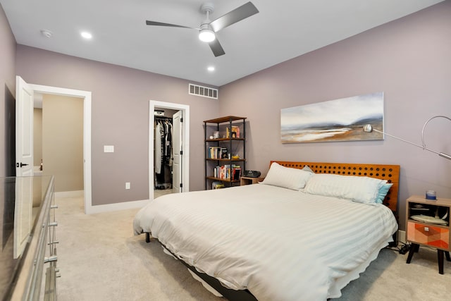 bedroom with a walk in closet, a closet, visible vents, and light carpet