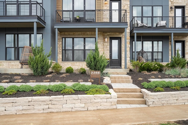 doorway to property featuring stone siding and a balcony