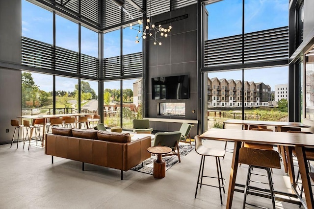 interior space featuring a wall of windows, a healthy amount of sunlight, a towering ceiling, and finished concrete floors