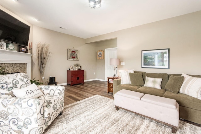 living room featuring a high end fireplace, baseboards, and wood finished floors