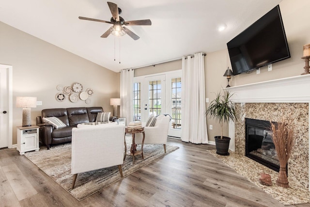 living area featuring a high end fireplace, baseboards, a ceiling fan, and wood finished floors