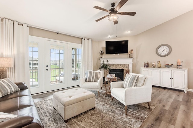 living room featuring a glass covered fireplace, light wood-style floors, lofted ceiling, and a ceiling fan