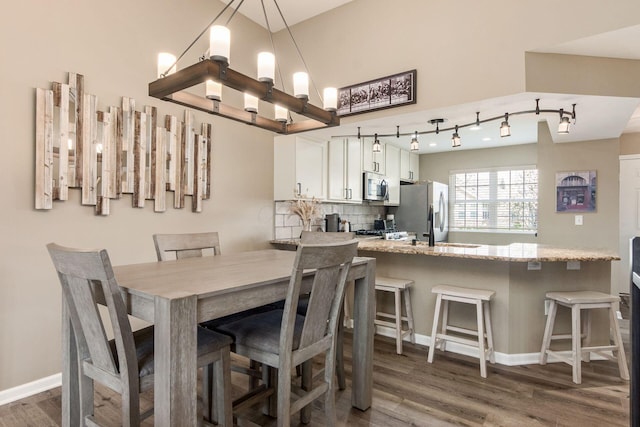 dining area with dark wood-type flooring, a chandelier, and baseboards