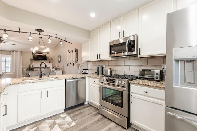 kitchen with a toaster, a sink, light stone countertops, decorative backsplash, and appliances with stainless steel finishes