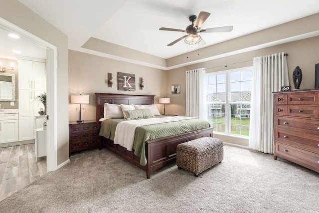 bedroom with light carpet, a ceiling fan, and ensuite bathroom