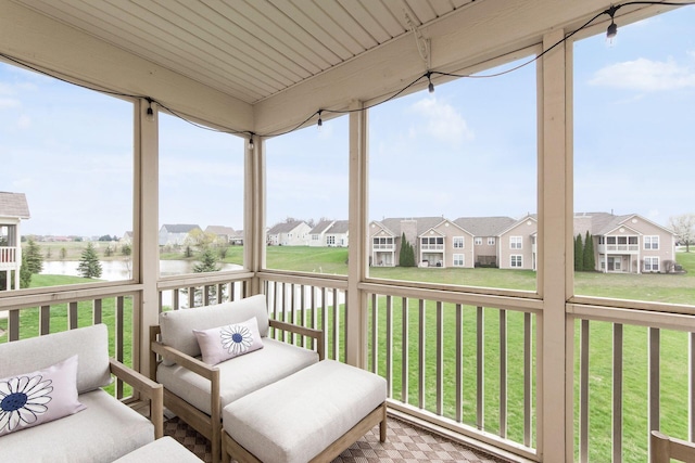 sunroom / solarium with plenty of natural light, a residential view, and a water view
