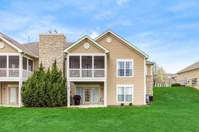 back of house with a lawn, a sunroom, a patio area, and cooling unit