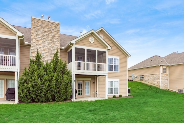 back of house with a lawn, a sunroom, and french doors