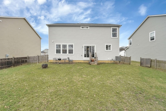 back of house with an outdoor fire pit, entry steps, a fenced backyard, and a lawn