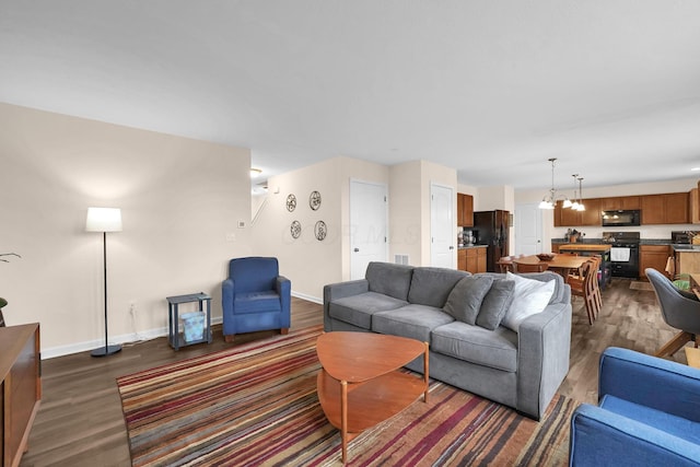 living room featuring dark wood-type flooring, baseboards, and a chandelier
