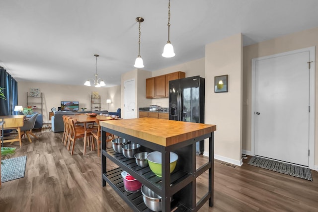 kitchen featuring visible vents, hanging light fixtures, black fridge, dark wood finished floors, and brown cabinets