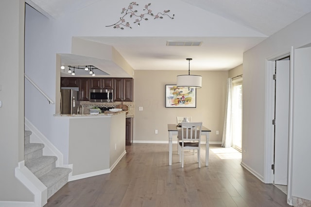 dining space featuring visible vents, wood finished floors, track lighting, baseboards, and lofted ceiling