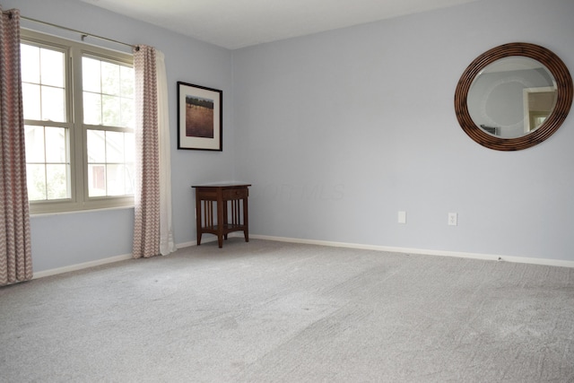 carpeted spare room featuring baseboards