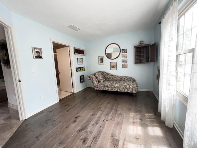 living area featuring a healthy amount of sunlight, baseboards, wood finished floors, and visible vents