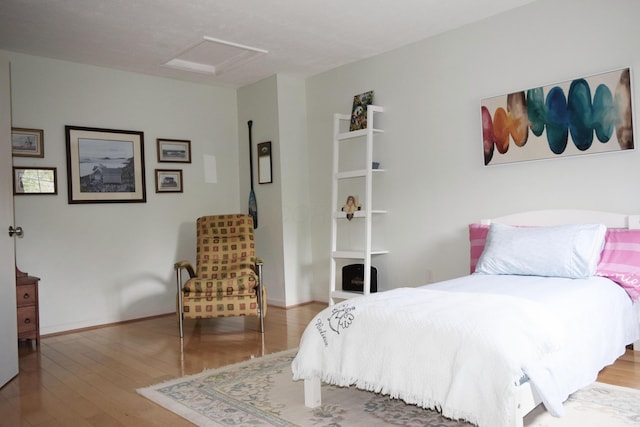 bedroom with baseboards, wood finished floors, and attic access