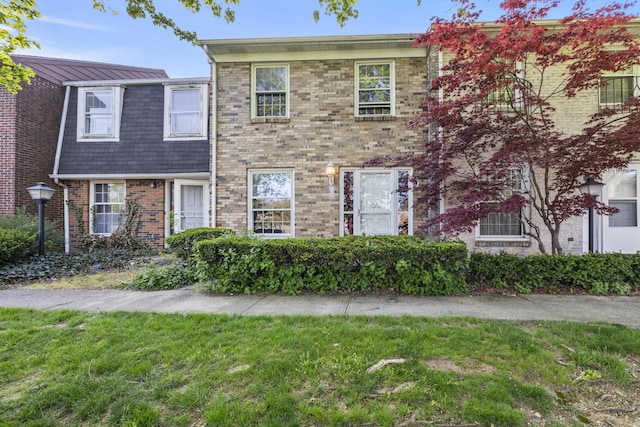 view of property with brick siding and a front yard