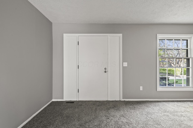 unfurnished room featuring baseboards, carpet flooring, and a textured ceiling