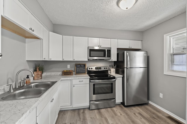 kitchen with white cabinets, stainless steel appliances, a sink, light wood-type flooring, and visible vents