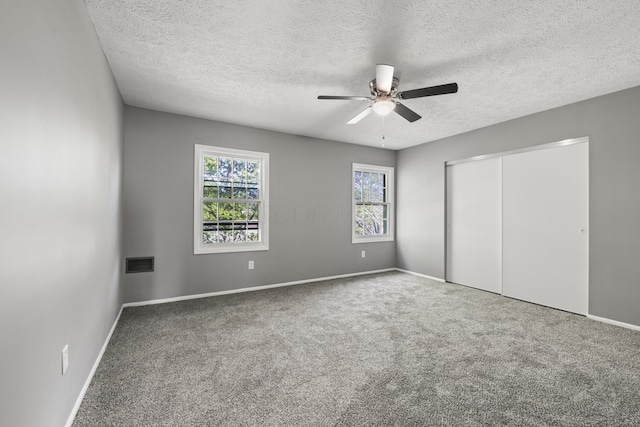 unfurnished bedroom featuring visible vents, a closet, baseboards, a textured ceiling, and carpet flooring