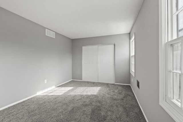 unfurnished bedroom featuring baseboards, carpet flooring, visible vents, and a closet