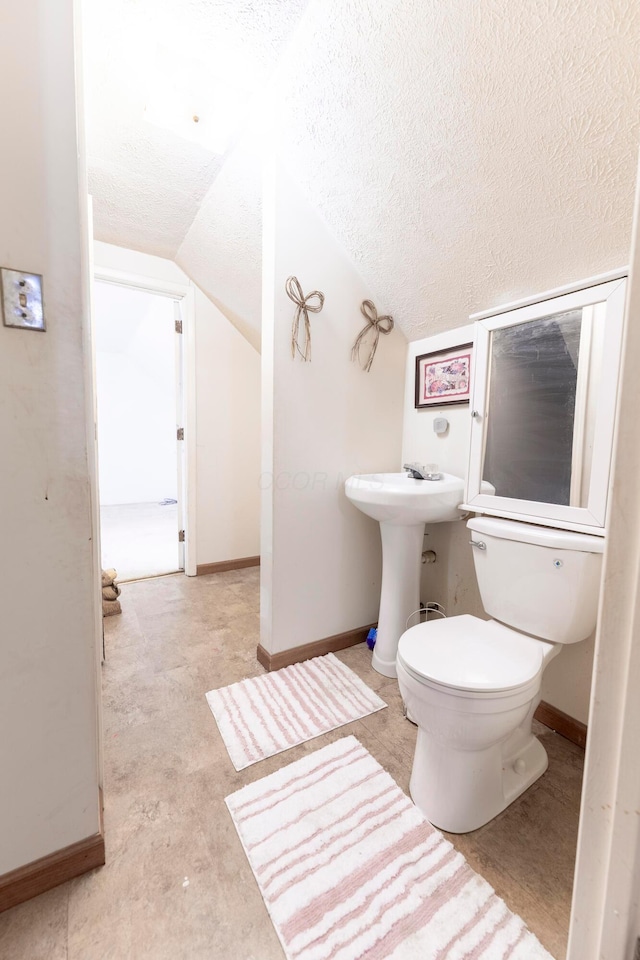 bathroom featuring lofted ceiling, baseboards, and a textured ceiling
