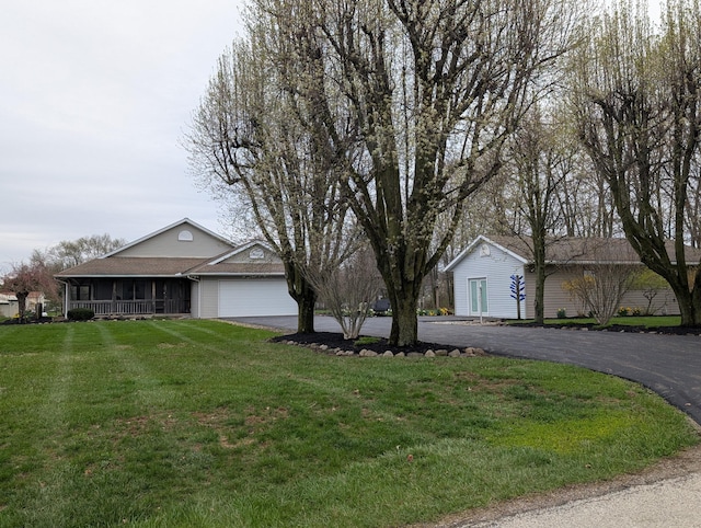 ranch-style home featuring an attached garage, a front lawn, and aphalt driveway