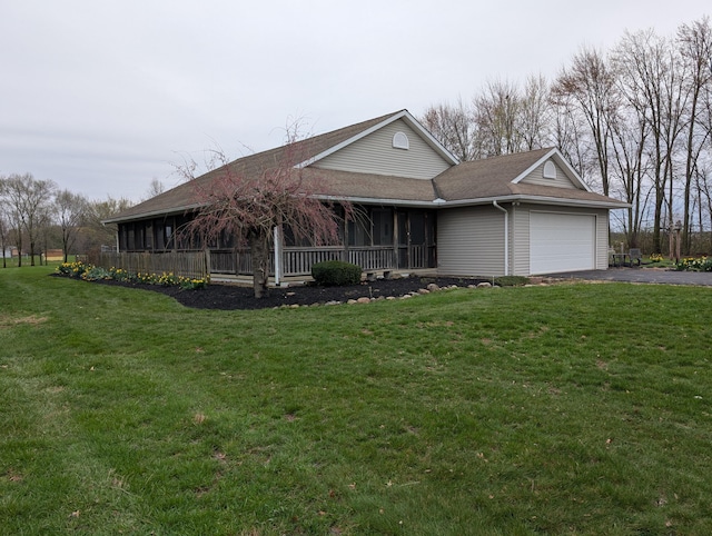 view of front of property featuring aphalt driveway, a sunroom, a front yard, an attached garage, and a shingled roof