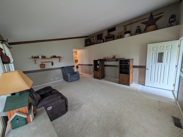 carpeted living area featuring vaulted ceiling, wainscoting, and visible vents