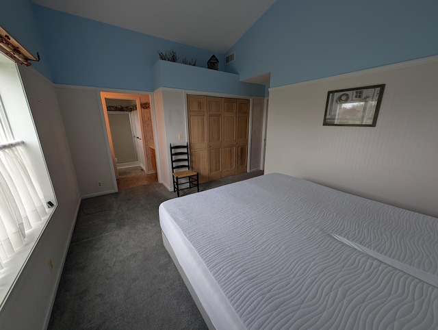 unfurnished bedroom featuring dark carpet, a closet, high vaulted ceiling, and visible vents