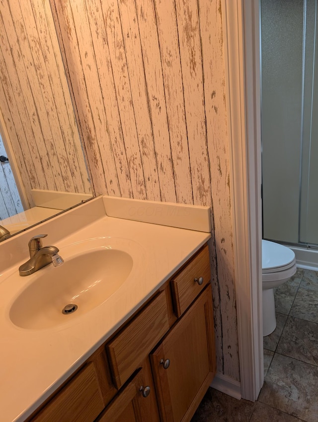 bathroom featuring toilet, wallpapered walls, and a shower stall